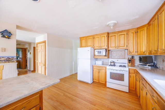 kitchen with light countertops, light wood-type flooring, decorative backsplash, and white appliances