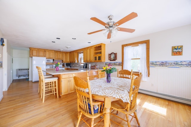 dining room featuring light wood-style flooring, a wealth of natural light, heating unit, and a ceiling fan