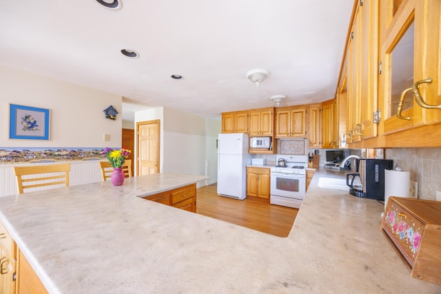 kitchen with backsplash, white appliances, light countertops, and a sink