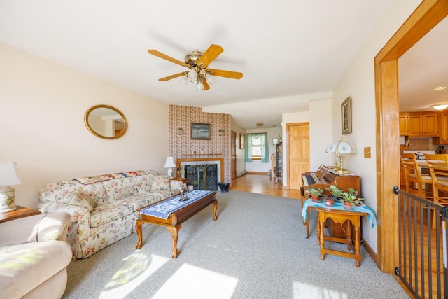 living area with a ceiling fan, baseboards, a fireplace, and carpet