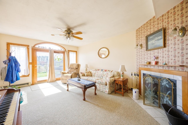 living area with wallpapered walls, a tiled fireplace, and ceiling fan