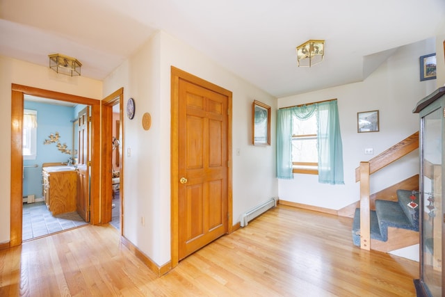 foyer entrance featuring baseboards, light wood-style floors, baseboard heating, and stairway