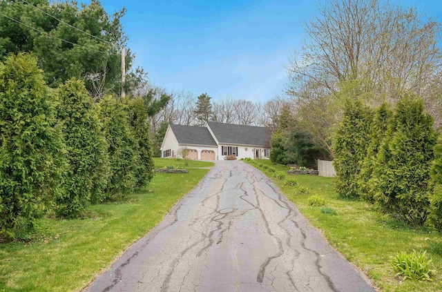 ranch-style home with a front lawn, a garage, and aphalt driveway