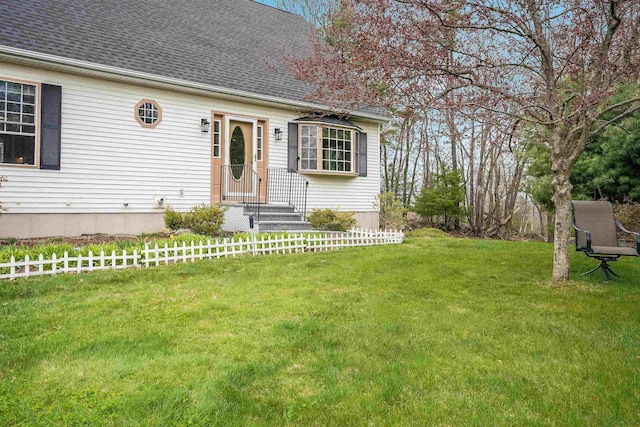 view of front of house with a front lawn, roof with shingles, and fence