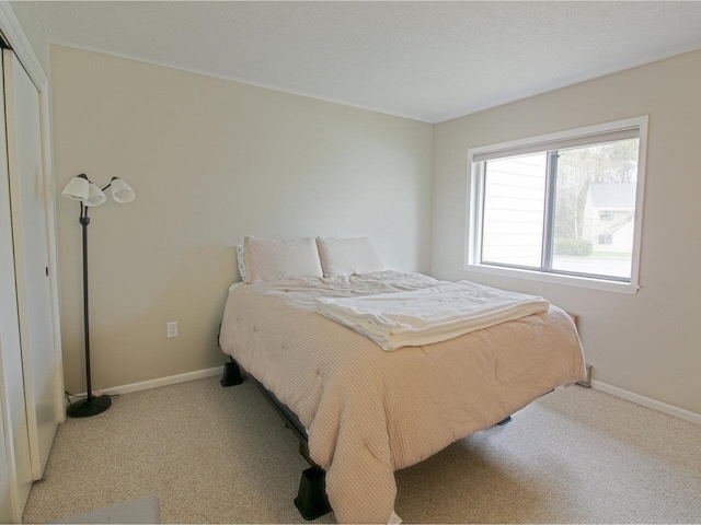 bedroom with light colored carpet and baseboards
