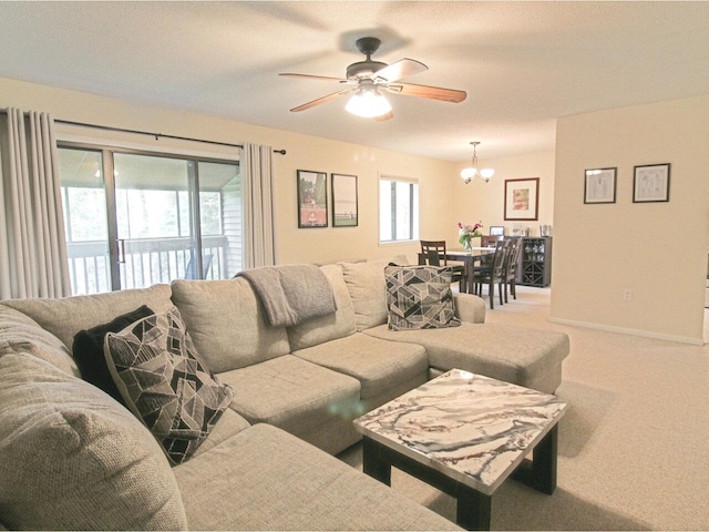 living room featuring light carpet, ceiling fan with notable chandelier, and baseboards