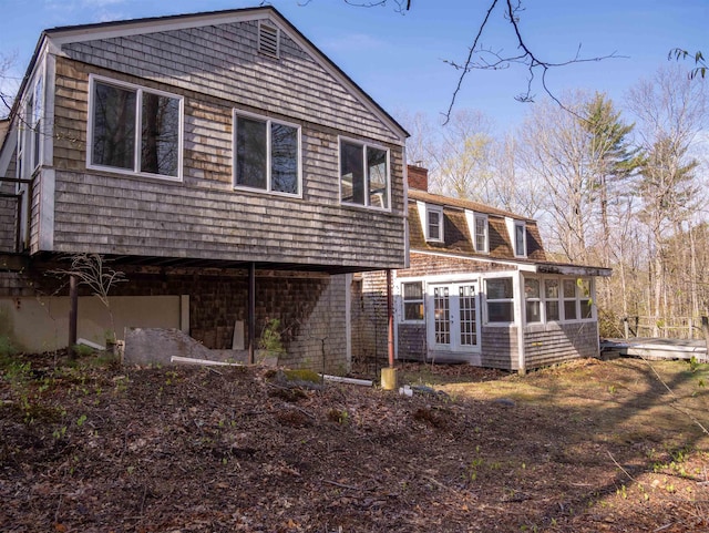 rear view of house featuring a chimney, french doors, and a sunroom