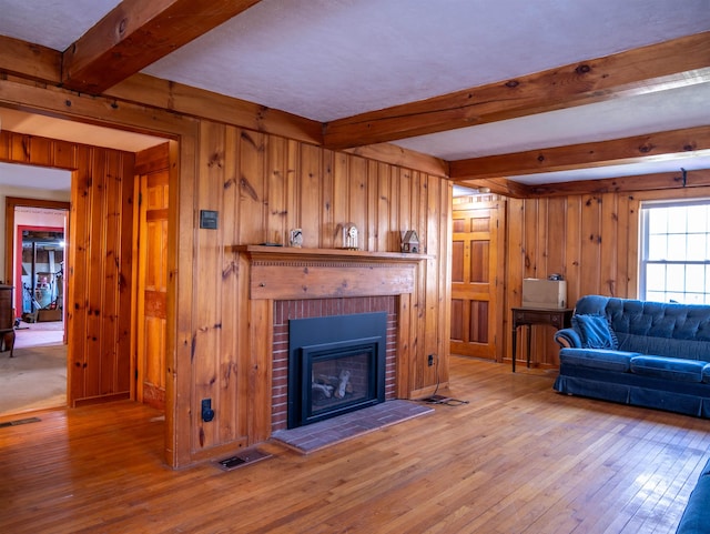 living area with hardwood / wood-style flooring, beamed ceiling, and wood walls
