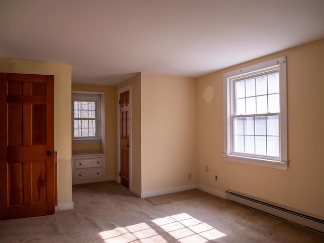 spare room with light carpet, baseboards, and a baseboard heating unit