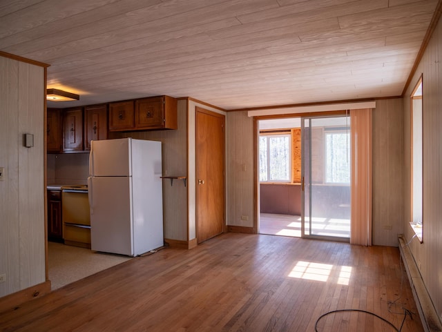 kitchen with brown cabinets, freestanding refrigerator, baseboard heating, stove, and light wood-style floors
