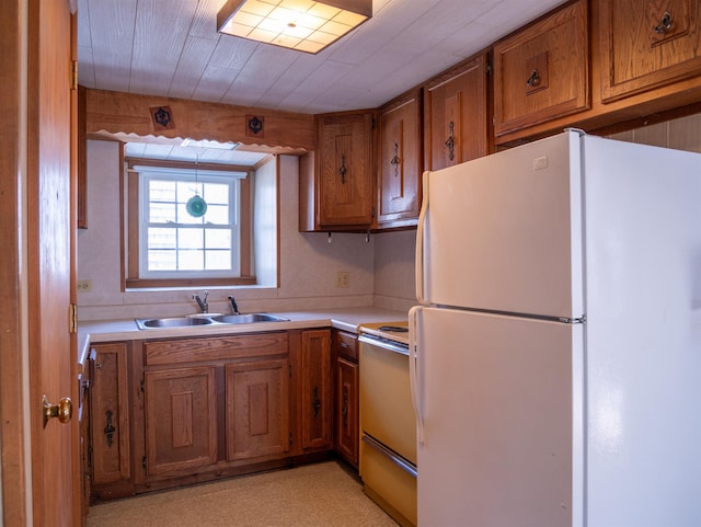 kitchen with freestanding refrigerator, brown cabinets, range with electric cooktop, and a sink