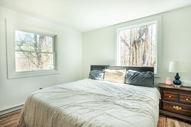 bedroom featuring a baseboard radiator, wood finished floors, and multiple windows