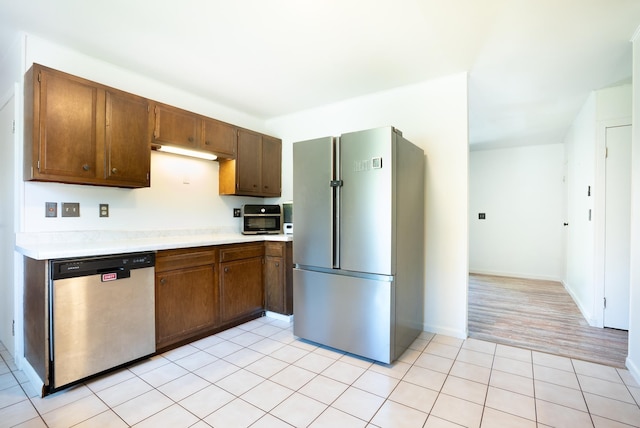 kitchen featuring light tile patterned floors, baseboards, light countertops, and appliances with stainless steel finishes