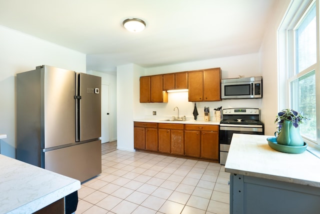 kitchen featuring light countertops, appliances with stainless steel finishes, brown cabinets, and a sink