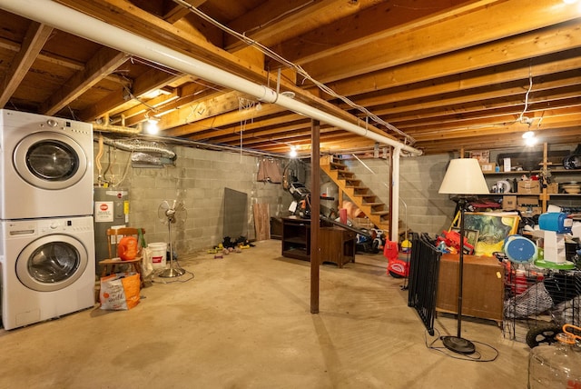 unfinished basement featuring water heater, stairway, and stacked washer / drying machine