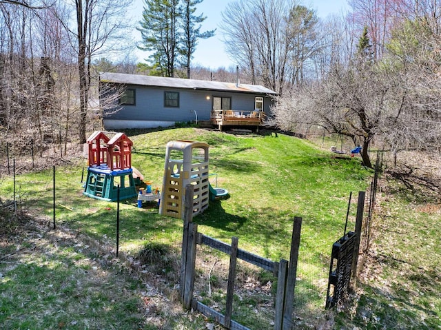 rear view of property with a playground, fence, a deck, and a lawn