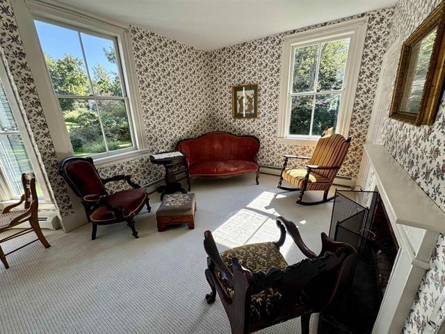 living area with carpet floors, baseboard heating, and wallpapered walls