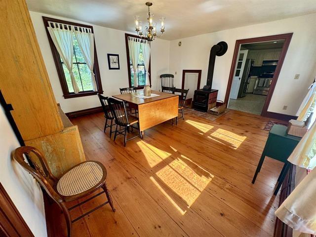 dining room with a wood stove, baseboards, hardwood / wood-style floors, and an inviting chandelier