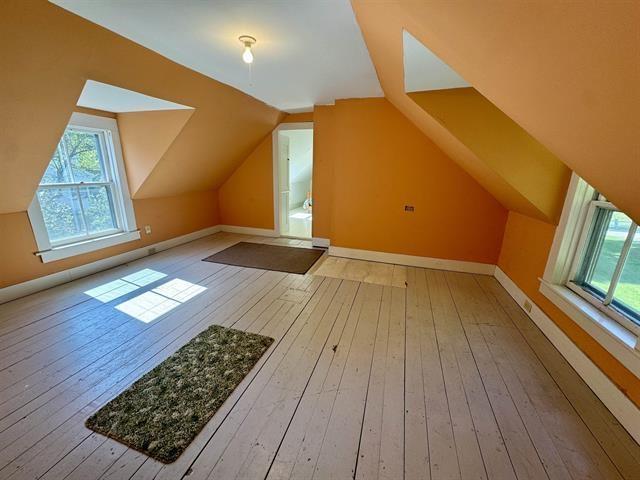 additional living space featuring vaulted ceiling, baseboards, and hardwood / wood-style floors