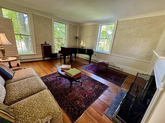 living area featuring a baseboard radiator, ornamental molding, and wood finished floors