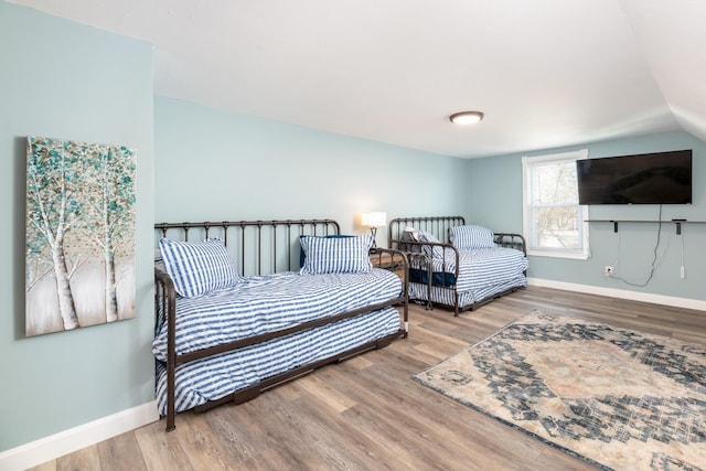 bedroom featuring vaulted ceiling, wood finished floors, and baseboards