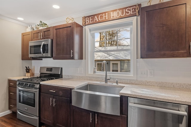 kitchen featuring a sink, stainless steel appliances, ornamental molding, light stone counters, and decorative backsplash