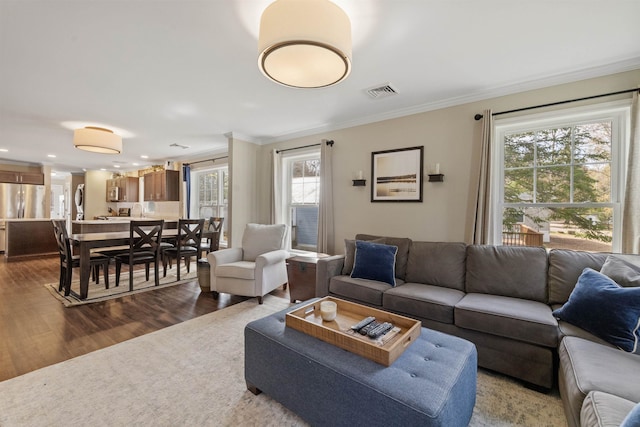 living area with dark wood finished floors, visible vents, and ornamental molding