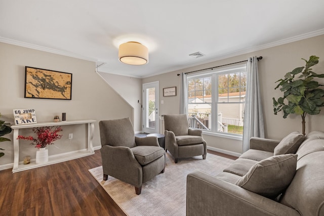 living room featuring visible vents, wood finished floors, baseboards, and ornamental molding