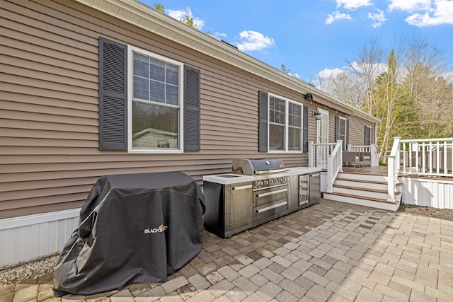 view of patio with a wooden deck, exterior kitchen, and grilling area