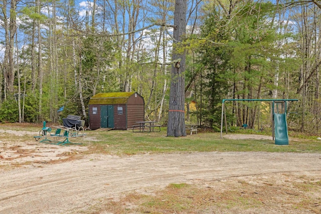 view of yard featuring a playground, an outdoor structure, and a storage unit