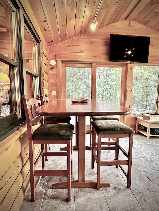 dining space featuring wooden ceiling, vaulted ceiling, and wooden walls