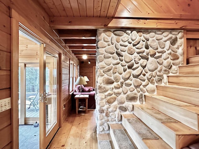 stairs with french doors, wood ceiling, wood walls, hardwood / wood-style flooring, and beam ceiling