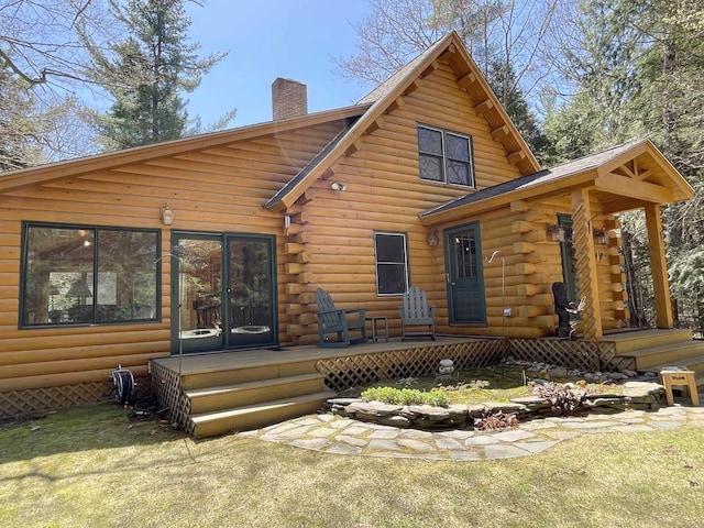 rear view of property with a lawn, log siding, a chimney, and a wooden deck