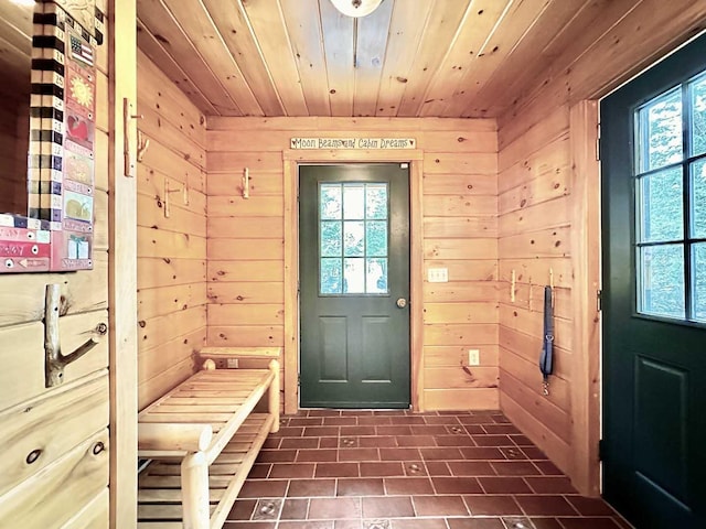 mudroom featuring wood walls, dark tile patterned flooring, and wooden ceiling