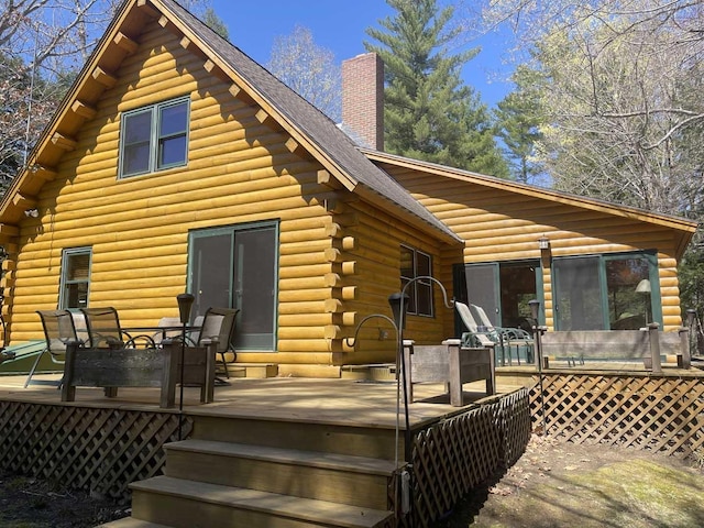 rear view of house featuring a chimney, log exterior, and a deck
