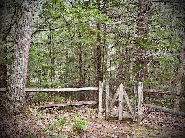 view of gate featuring fence and a view of trees