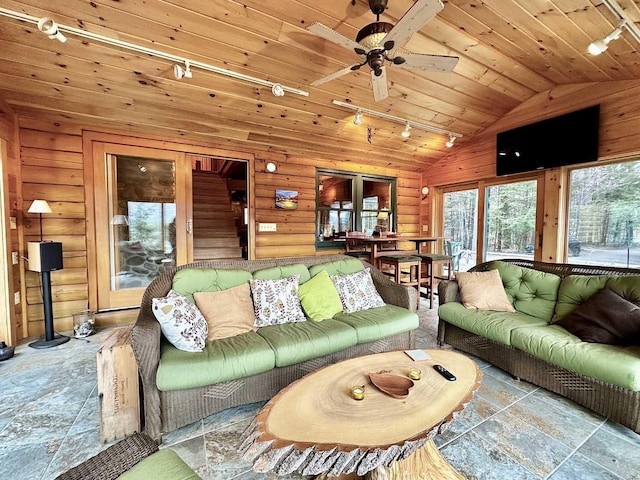 living room with lofted ceiling, stone finish floor, track lighting, ceiling fan, and wood ceiling