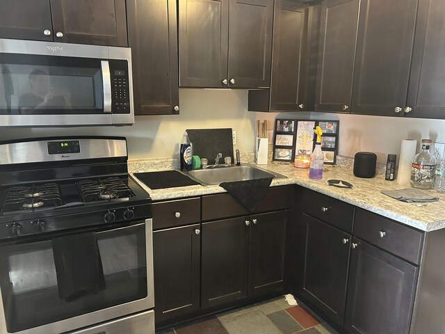 124 Mammoth Rd Unit 206, Hooksett, NH 03106 - kitchen with stainless steel microwave, gas stove, a sink, light stone counters, and dark brown cabinetry