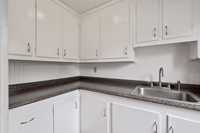 kitchen with a sink, dark countertops, and white cabinets