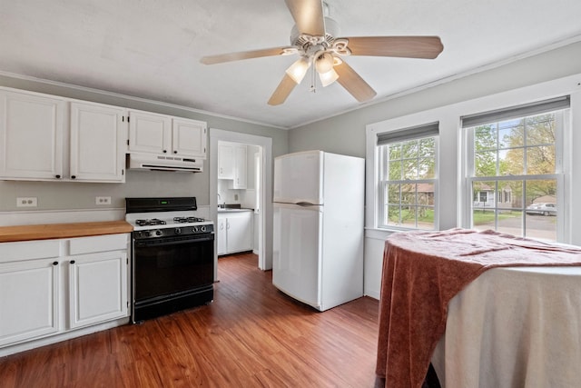 kitchen featuring wood finished floors, freestanding refrigerator, under cabinet range hood, gas range, and white cabinets