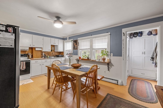dining area featuring crown molding, ceiling fan, baseboard heating, and light wood-style floors