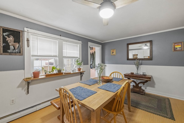 dining area featuring a baseboard heating unit, ornamental molding, ceiling fan, and wood finished floors