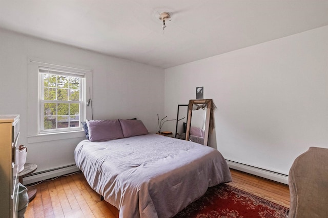 bedroom featuring hardwood / wood-style flooring and a baseboard heating unit