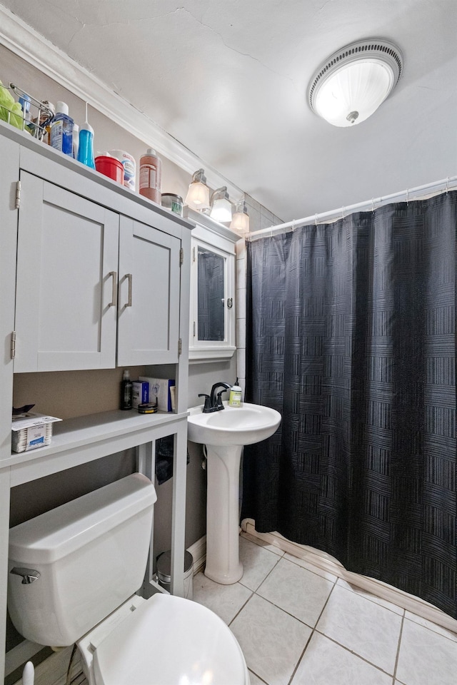 bathroom featuring toilet, tile patterned flooring, a shower with curtain, and a sink