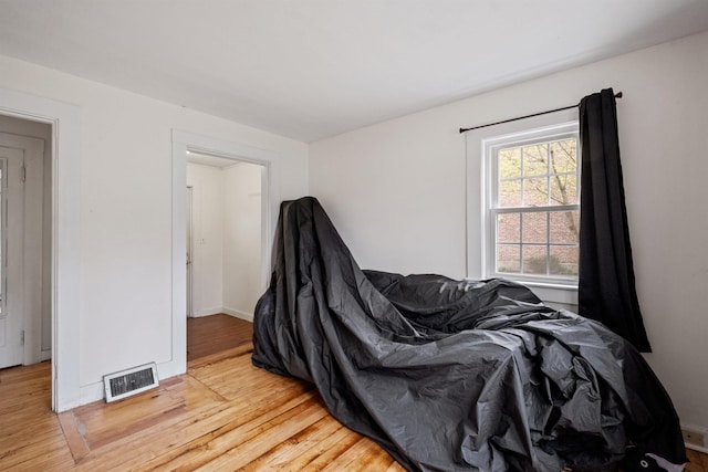 bedroom with light wood finished floors, visible vents, and baseboards