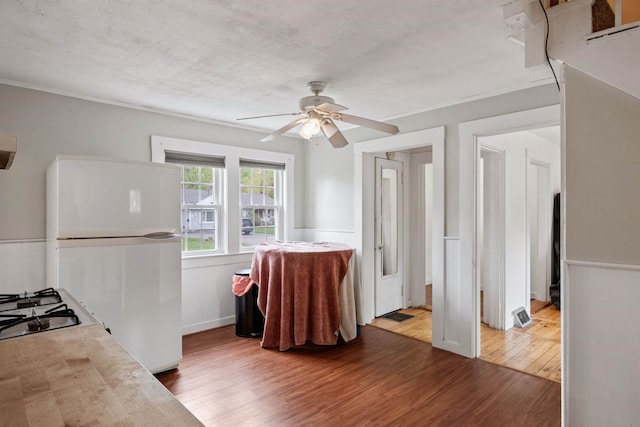 interior space with freestanding refrigerator, light countertops, wood finished floors, and ceiling fan