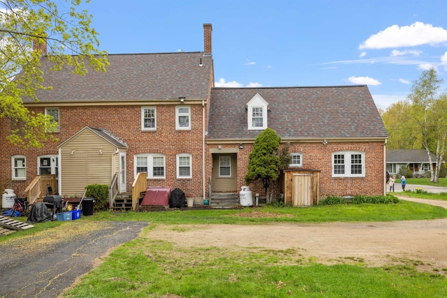 back of property featuring a chimney, brick siding, and roof with shingles
