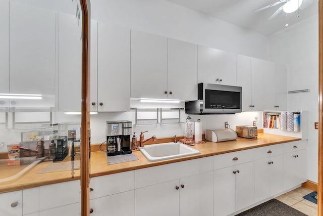 kitchen with white cabinets, light countertops, stainless steel microwave, and a sink