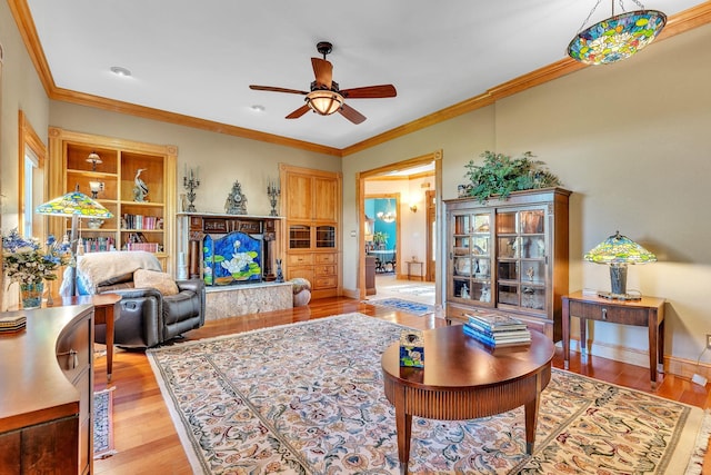 living room featuring baseboards, ornamental molding, light wood finished floors, and ceiling fan