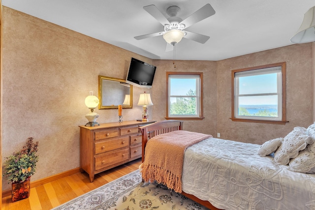 bedroom with ceiling fan, baseboards, and light wood-style floors